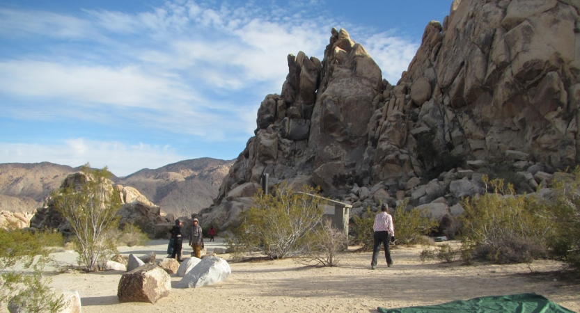 A group of veterans set up camp amount tall rock formations in joshua tree.